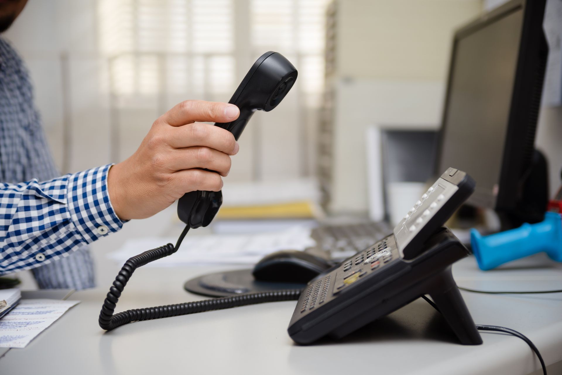 Closeup of businessman dialing making office phonecall, light table background. Corporate male holding telephone handle digital electronic pc connection checking daily data news, online chat talk job