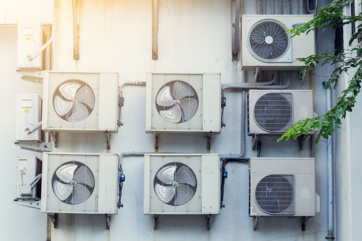 Air conditioner outdoor unit on white wall of building for temperature in the building to cool. They are install with metal steel framework outdoors building.